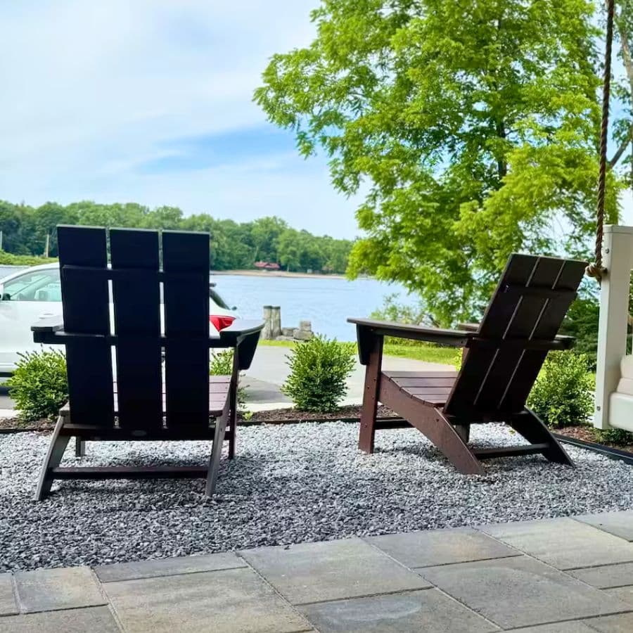 Two wooden chairs facing a tranquil lake surrounded by greenery.