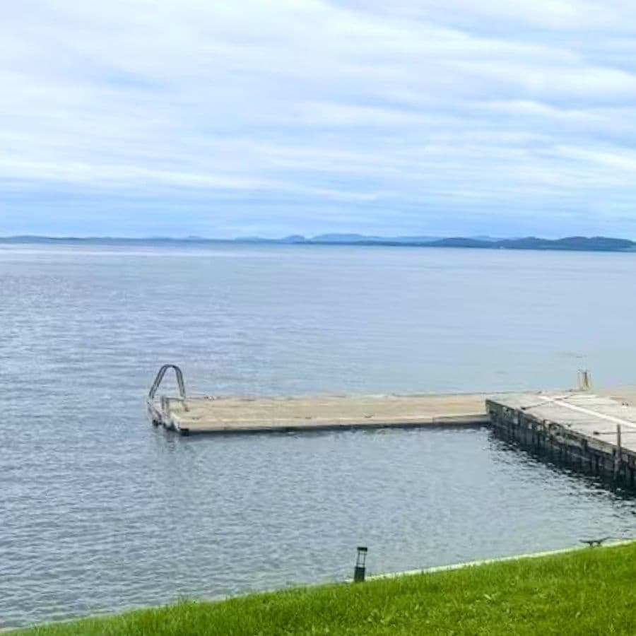 A wooden dock extends into a calm body of water under a cloudy sky.